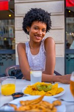 Cute beauty african woman smiling at camera sitting in a fast food mexican restaurant