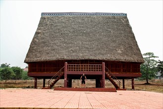 A tourist exploring a traditional architecture of a Bahnar ethnic stilt house or Rong House in