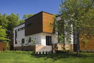 Beige stone with brown stained cedar wood modern cubist style residential home facade in spring,