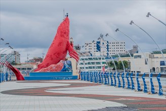 Waterfront promenade with a large red sculpture and sweeping streetlights, in Ulsan, South Korea,