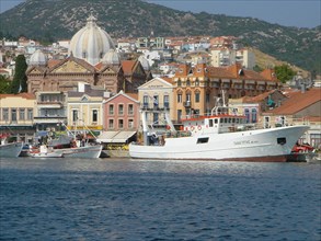 View of a coastal town with historic buildings and boats in front of a hilly landscape Elba Island