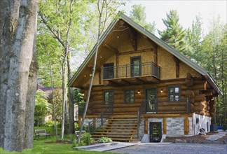 Luxurious two story Scandinavian style log cabin home facade in late spring, Quebec, Canada, North