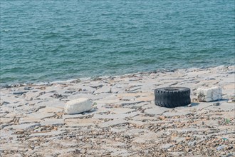 Discarded tire near the sea, illustrating marine pollution, in South Korea