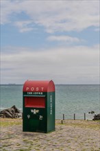 Red and green post box by the ocean with a cloudy sky above, in Ulsan, South Korea, Asia