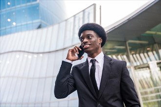 Close-up low angle view portrait of a young african businessman talking to the mobile outdoors