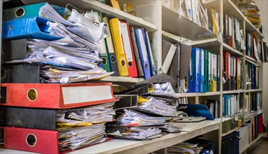 Many cluttered and chaotic files on shelves in an office, symbol bureaucracy, AI generated, AI