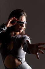 Studio portrait with grey background of a futuristic woman experiencing the metaverse world
