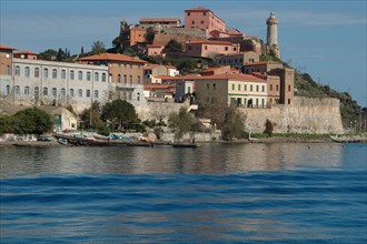 View of a coastal town with historic architecture and a lighthouse by day Elba Island Italy