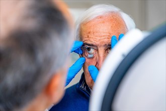 Ophthalmologist placing an eye opener to a senior man preparing him for a laser treatment for