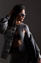 Vertical studio portrait with grey background of a futuristic woman in fashion clothes wearing