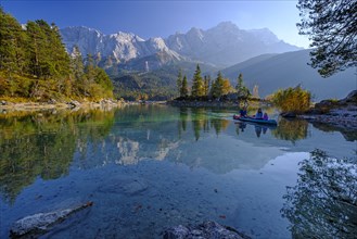 Canoeists on a mountain lake in front of steep mountains, reflection, evening light, autumn, Eibsee