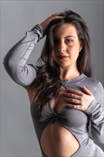 Studio photo with grey background of a beauty model posing with sensual gestures wearing long night