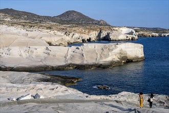 Two woman walking on the white rocks on the coast near Sarakinikoer, Milos, Cyclades, Greece,
