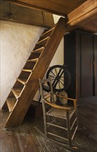 Antique rocking chair and spinning wheel next to Miller's stairs in master bedroom on upstairs