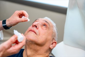 Ophthalmologist applies drops to dilate the pupil to a man before a glaucoma test on the eye with a