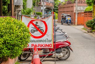 No parking sign displayed on a busy street with motorbikes in the background, in Chiang Mai,