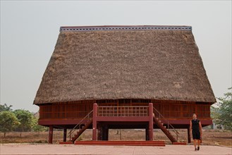 A tourist exploring a traditional architecture of a Bahnar ethnic stilt house or Rong House in