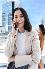 A woman is talking on her cell phone. She is smiling and she is in a good mood