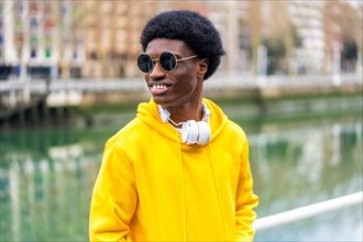 Stylish african man with sunglasses standing outdoors next to a urban river