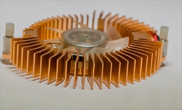 Closeup of round copper heat sink and plastic fan assembly on white background