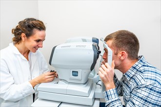 Side view of a female ophthalmologist scanning a man's eyes in the clinic