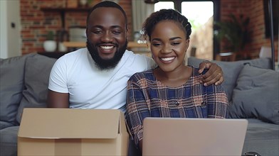 A smiling Mixed-race dark skinned couple unpacking boxes at home with a laptop on the table,