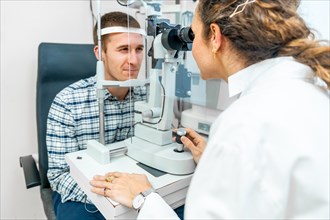 Smiling man checking the eye in an annual check up in the ophthalmologist