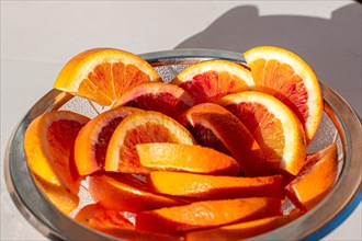 A glass bowl full of fresh orange slices in the sunlight