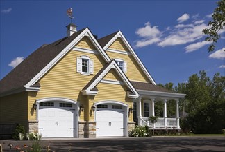 Yellow and white trim contemporary country house with two car garage, landscaped front yard and