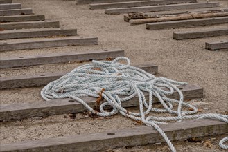 Coiled rope on wooden steps at a sandy beach setting, in Ulsan, South Korea, Asia