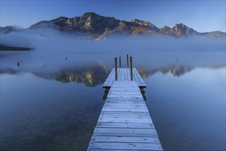 Morning atmosphere at mountain lake in front of mountains, footbridge, autumn, frost, fog,
