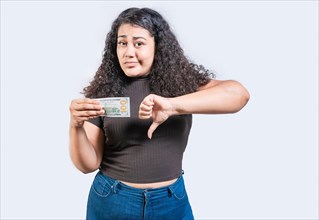 Displeased young woman holding a dollar bill with thumb down isolated. Sad girl holding a a 100