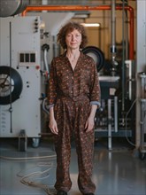 Confident technician in a patterned jumpsuit standing in front of industrial machinery with vibrant