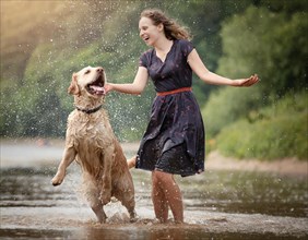 Labrador dog dirty muddy wet, shaking next to a woman in a dark summer dress, AI generated, AI