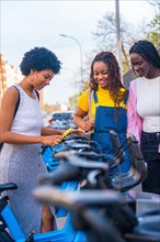 Vertical photo of three african girls using public bike in the city