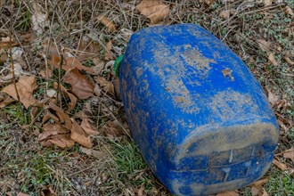 A faded blue barrel lies neglected among fallen leaves, in South Korea
