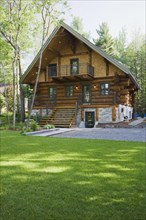 Luxurious two story Scandinavian style log cabin home facade in late spring, Quebec, Canada, North