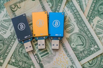 Blue and yellow USB hardware wallets with Bitcoin logos placed on US dollars, in South Korea