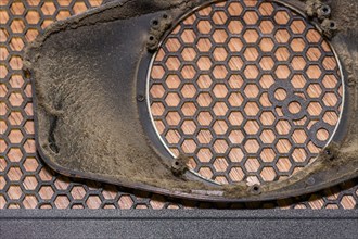 Close-up of a dusty electronic grille with a honeycomb pattern, in South Korea