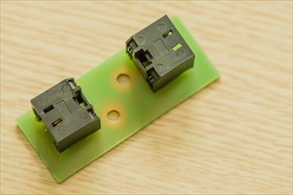 Two black plastic electrical connectors on a green circuit board, in South Korea