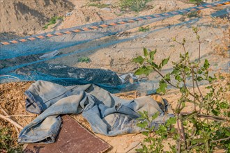 Pile of cast-off clothes and torn erosion net on natural ground, highlighting waste, in South Korea