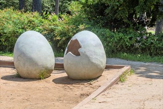 Two large egg sculptures, one cracked open, in a sandy park area, in Ulsan, South Korea, Asia