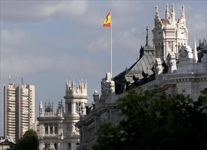 Spanish flag flies over opulent architecture under a cloudy sky Madrid Spain Postal building