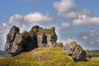 An old medieval ruined structure on a green meadow under a cloudy blue sky Ireland