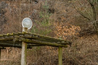 Halogen lamp in front of satellite TV dish on top of log structure in wooded mountainside park in