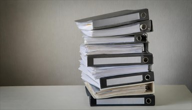 A high pile of files on a table symbolises a large workload, symbolism bureaucracy, AI generated,