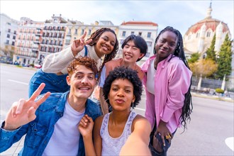 Multi-ethnic students gesturing success while taking a selfie in the city