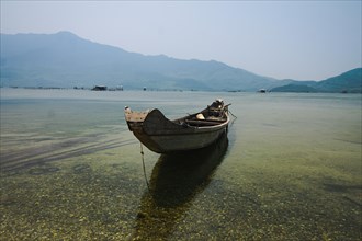 A solitary boat on still water with a clear mountain view, reflecting serenity and tranquility.