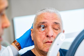 Ophthalmologist applying a tool to maintain the eye of a man opened for scan