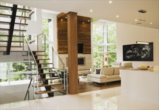 Wood, metal and glass staircase leading to living room with creamy beige L-shaped leather sofa